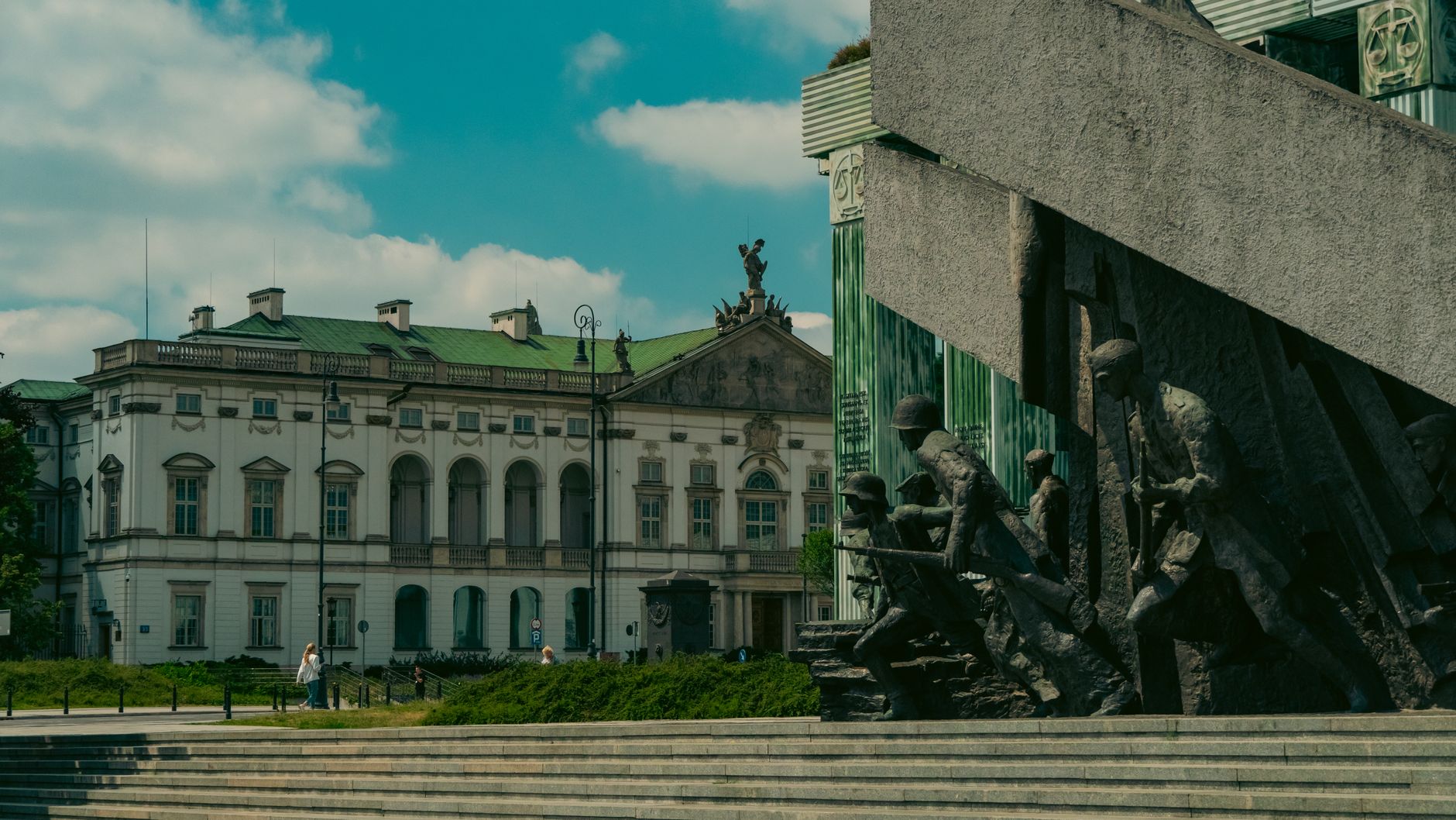 Warsaw Uprising Monument with a historic building in Warsaw, Poland under a blue sky.