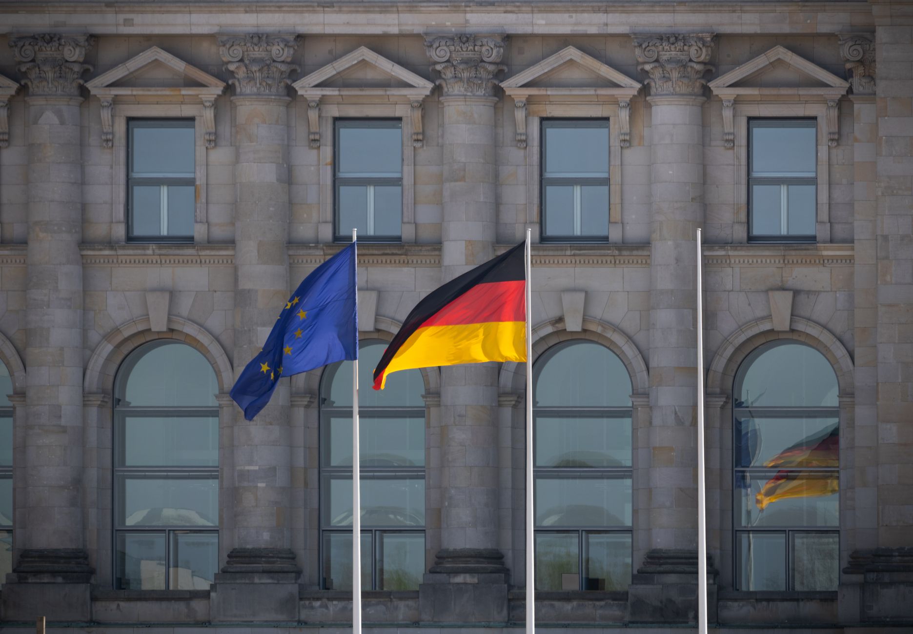 German and EU flags flying in front of the Reichstag building, Berlin, Germany.