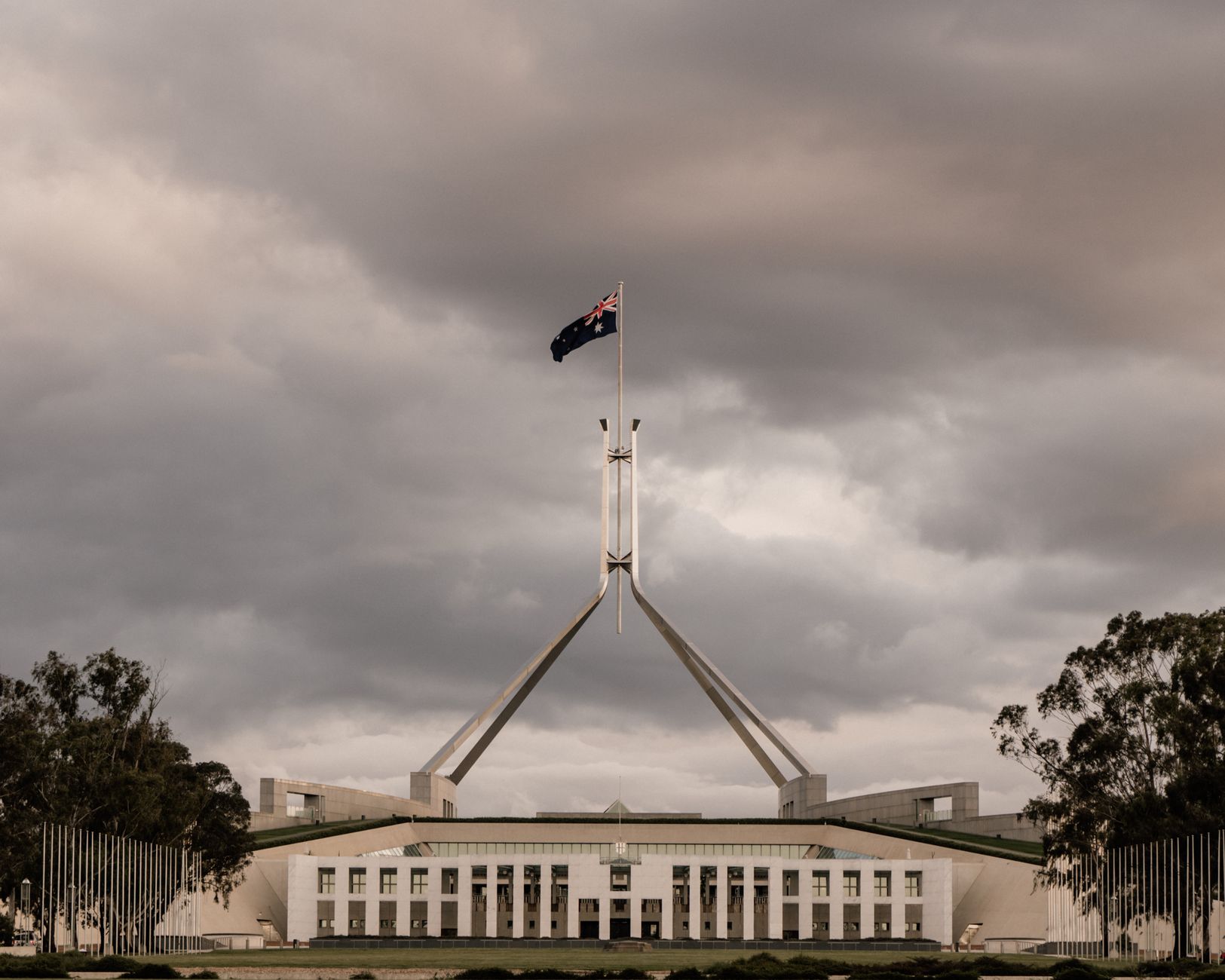 The Parliament House of Australia in Canberra with a dramatic cloudy backdrop.