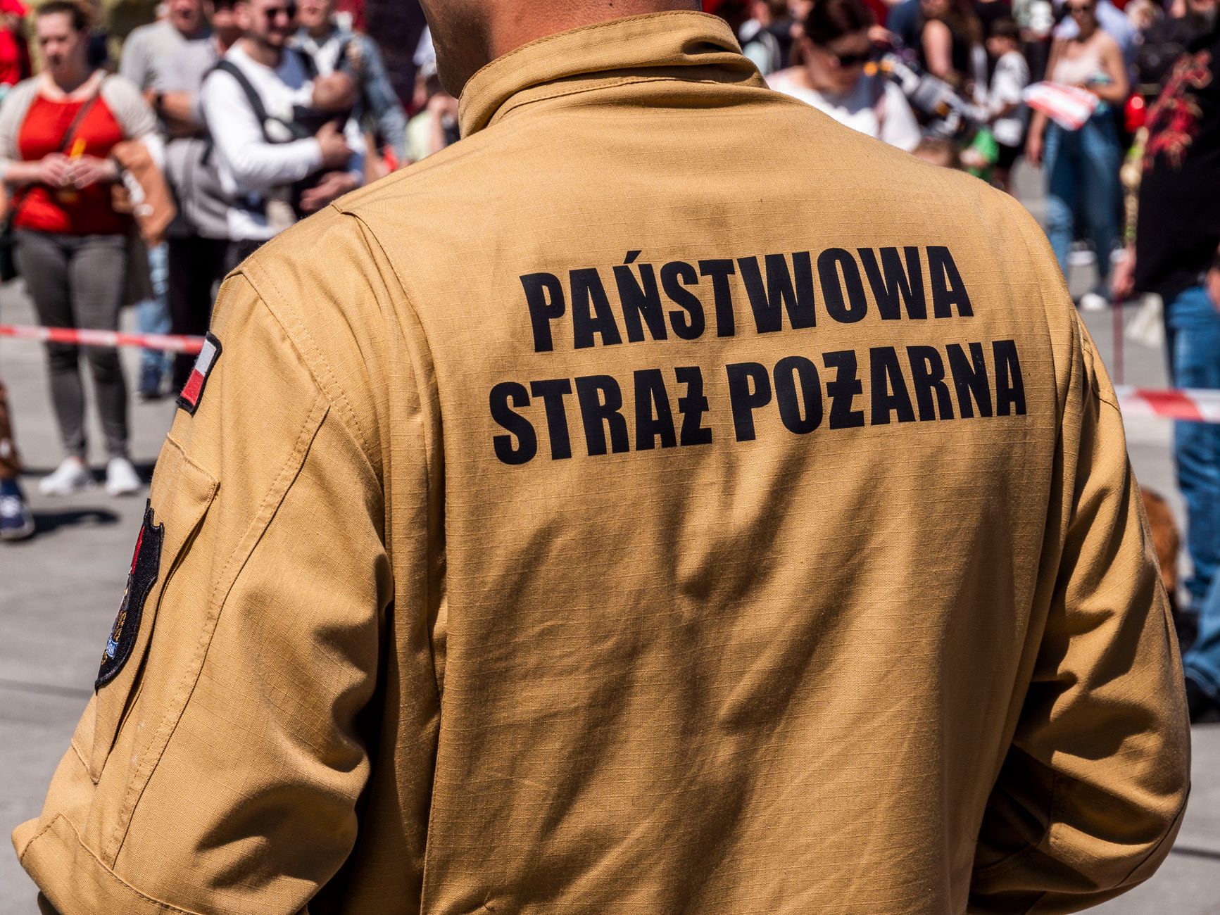 A Polish firefighter in uniform at a public event, surrounded by a crowd.