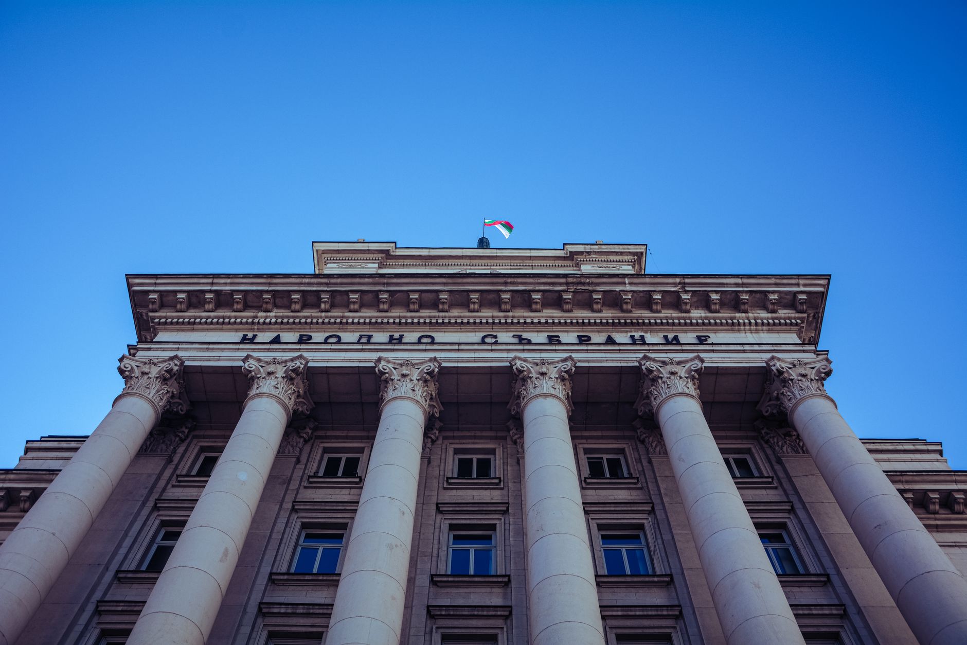 Low-angle view of Sofia's Parliament Building with majestic columns and clear sky.