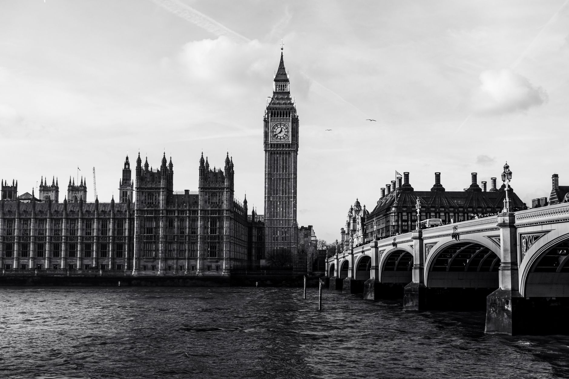 Black and white photo of Big Ben and Westminster Bridge over the River Thames in London.