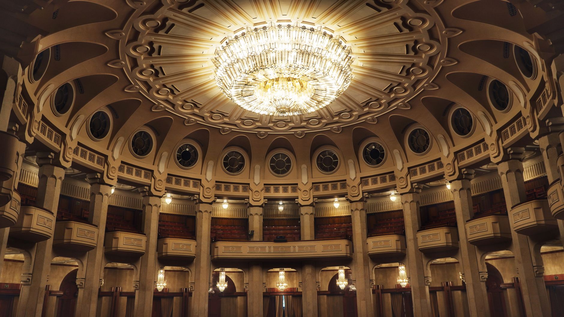 Elegant interior of Bucharest Parliament showcasing a grand chandelier and ornate architectural details.