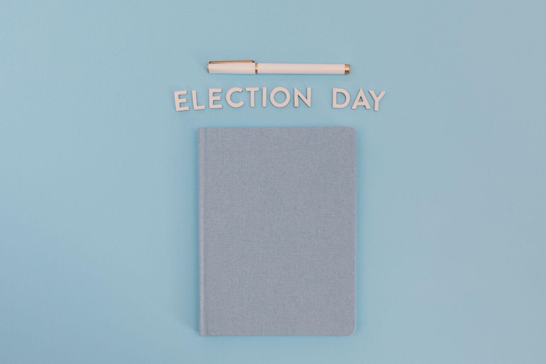 Flat lay of a notebook and pen with 'Election Day' text on a blue background.