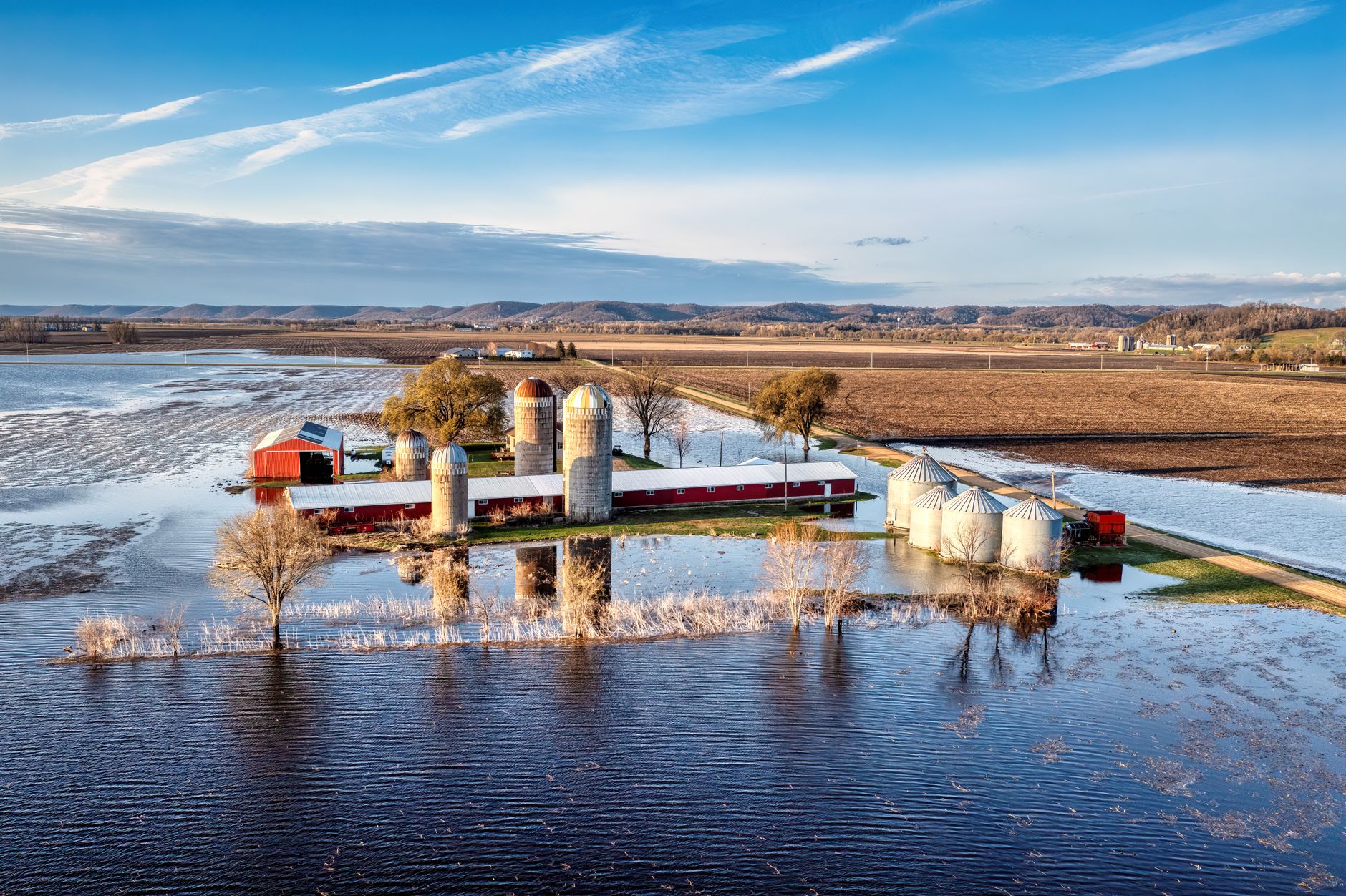 Aerial view of a rural farm with silos and flooded fields in Kellogg, Minnesota showing springtime landscape.