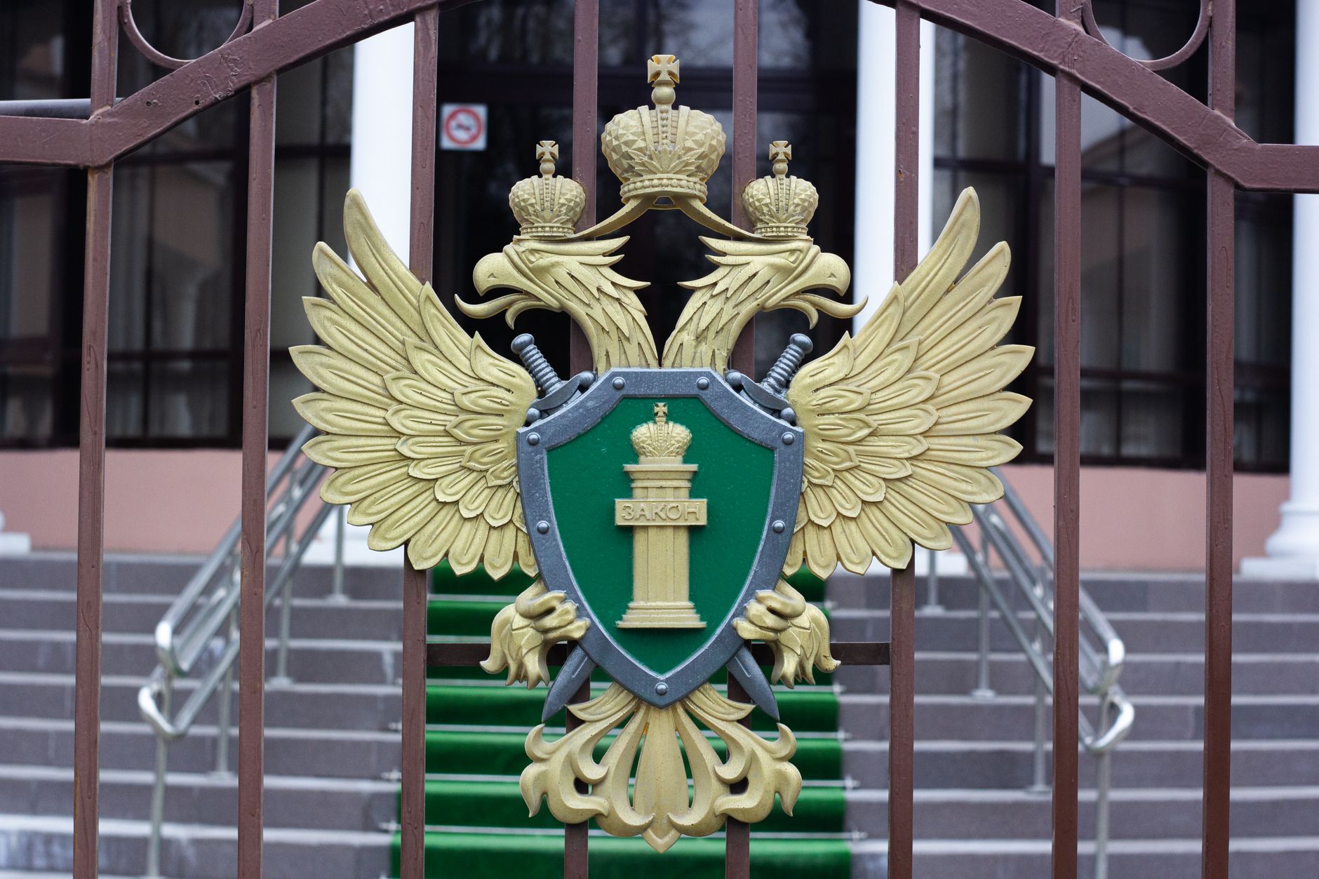 Close-up of a golden emblem with a double-headed eagle on an iron gate, signifying luxury and authority.