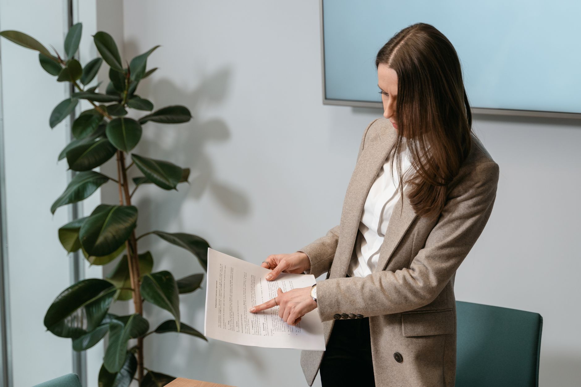 Professional woman in a brown blazer reviewing a document in an office setting.
