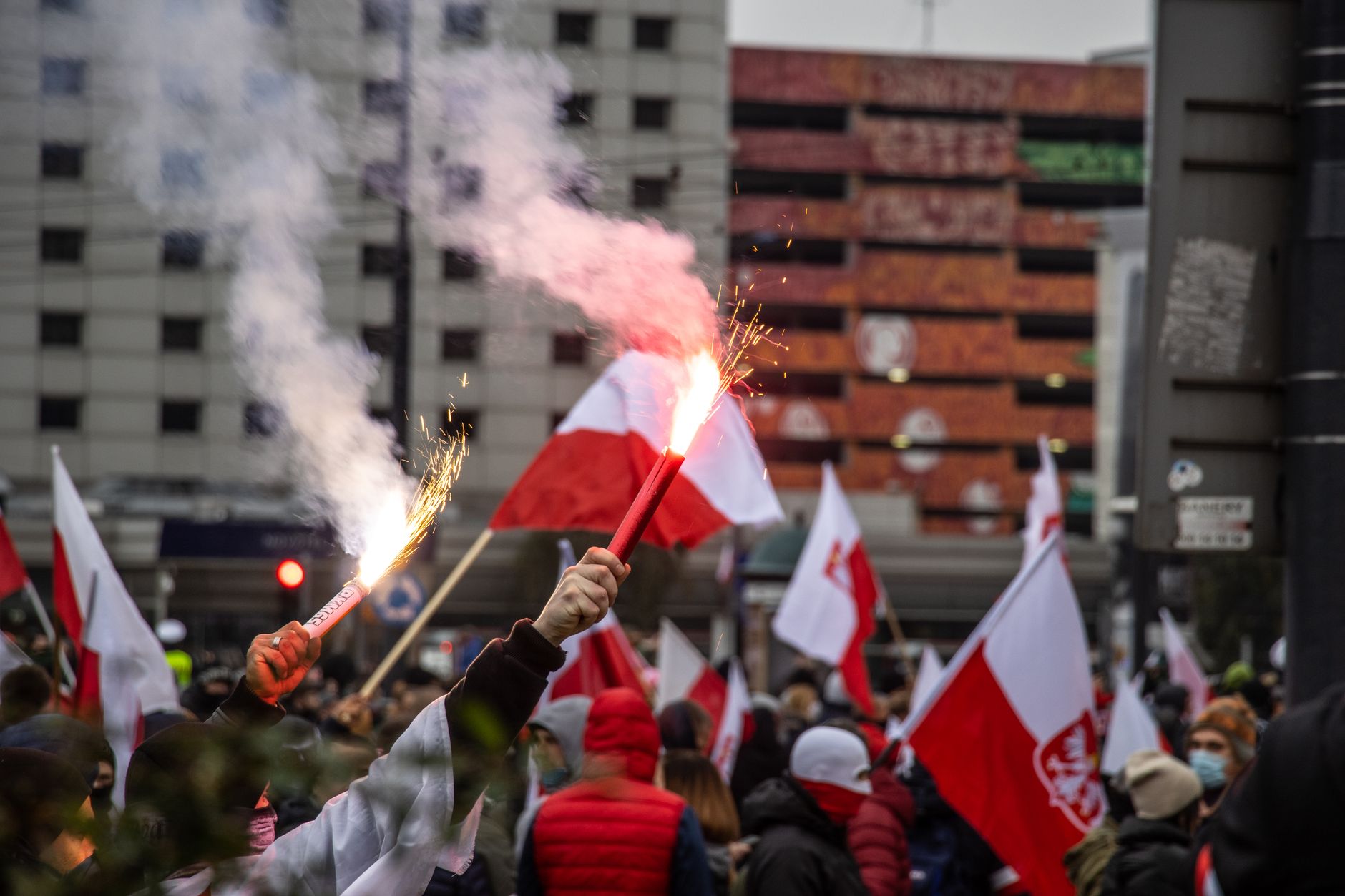 Crowd in Warsaw waving flags and flares during a patriotic demonstration.