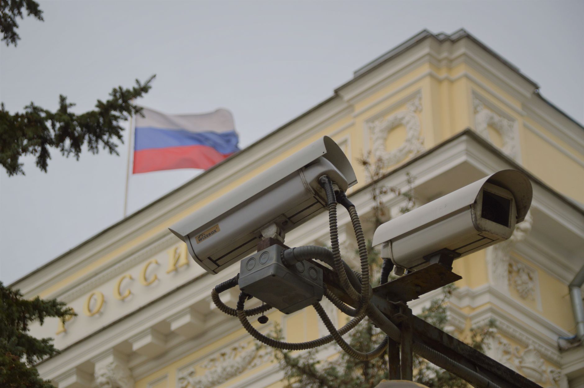 Close-up of surveillance cameras on a Russian building facade with flag.