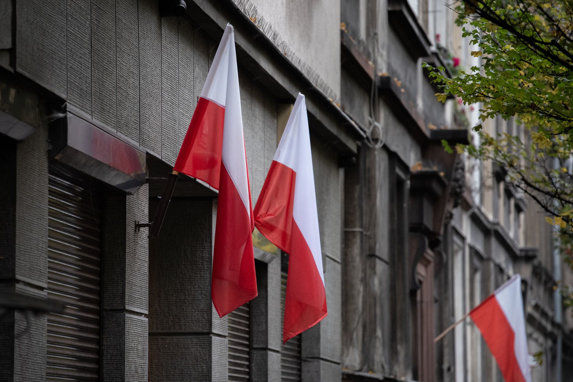 Polish flags hanging on a historic urban building, symbolizing national pride.