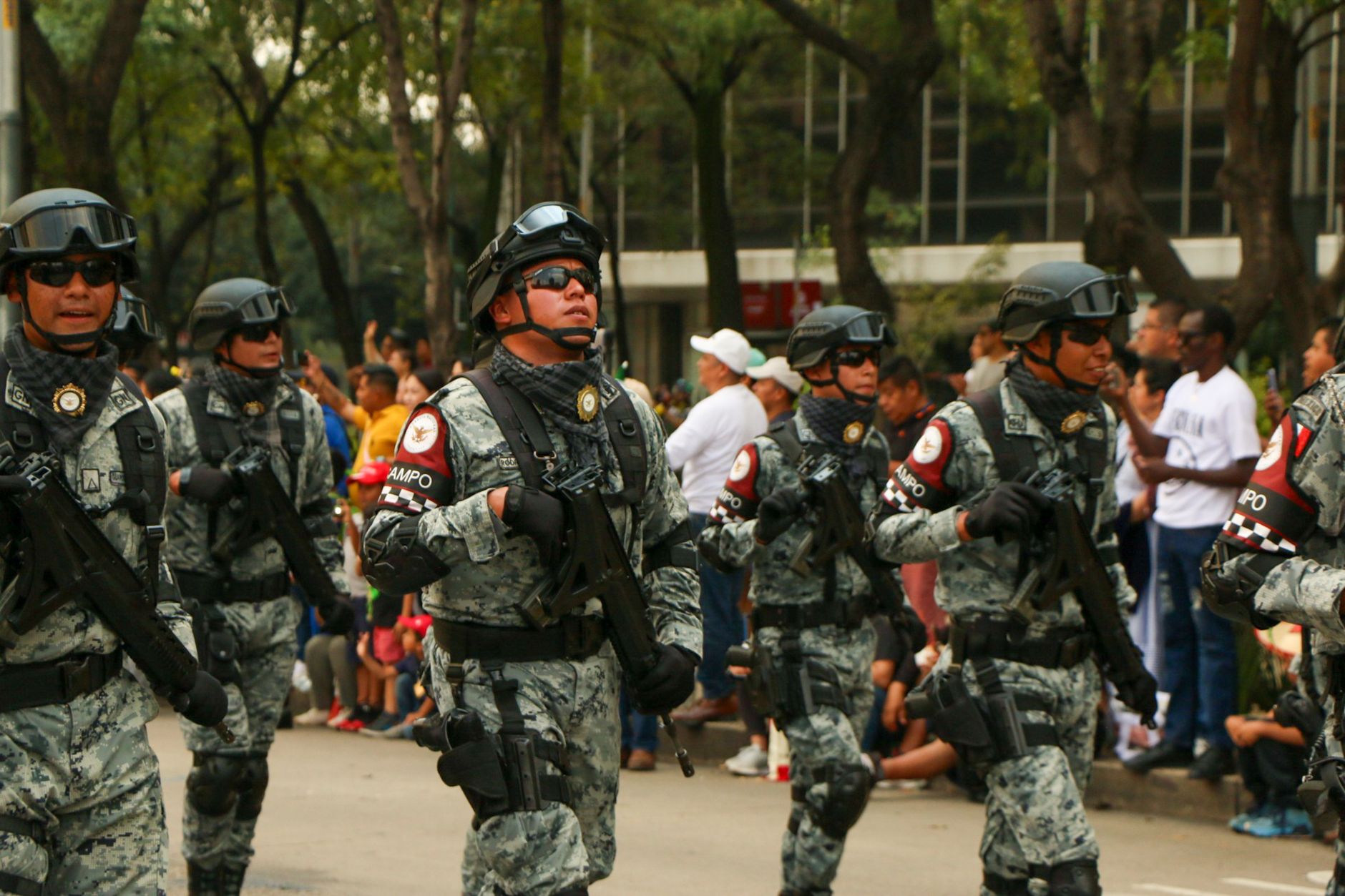 A military parade showcasing armed forces in uniform and tactical gear, marching in formation.