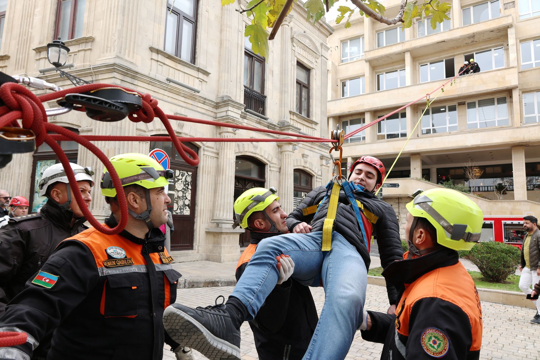 Firefighters perform a rescue operation during an emergency response drill in a city setting.