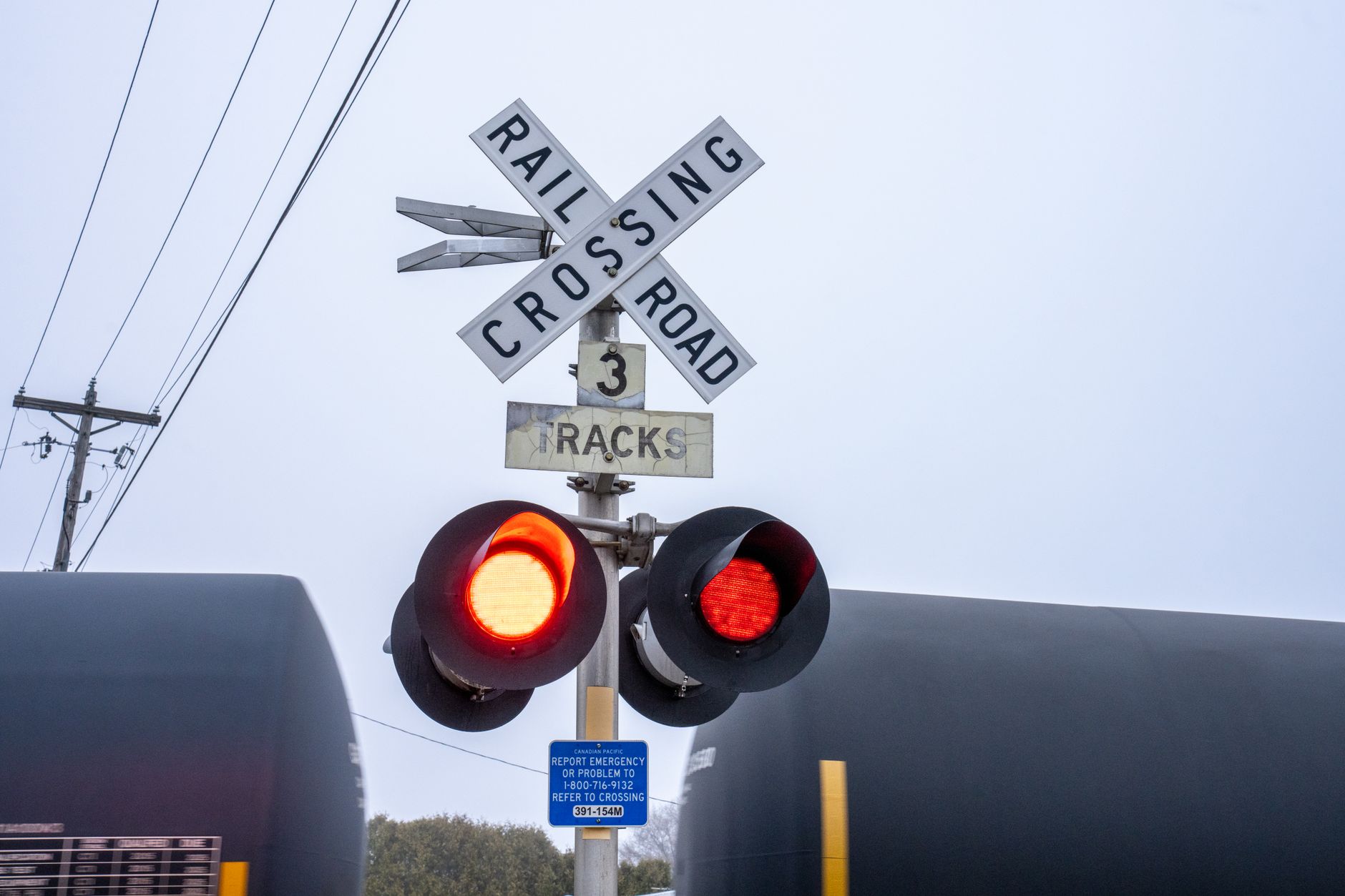 Railroad crossing with lit red warning lights and train passing in Wabasha, Minnesota.