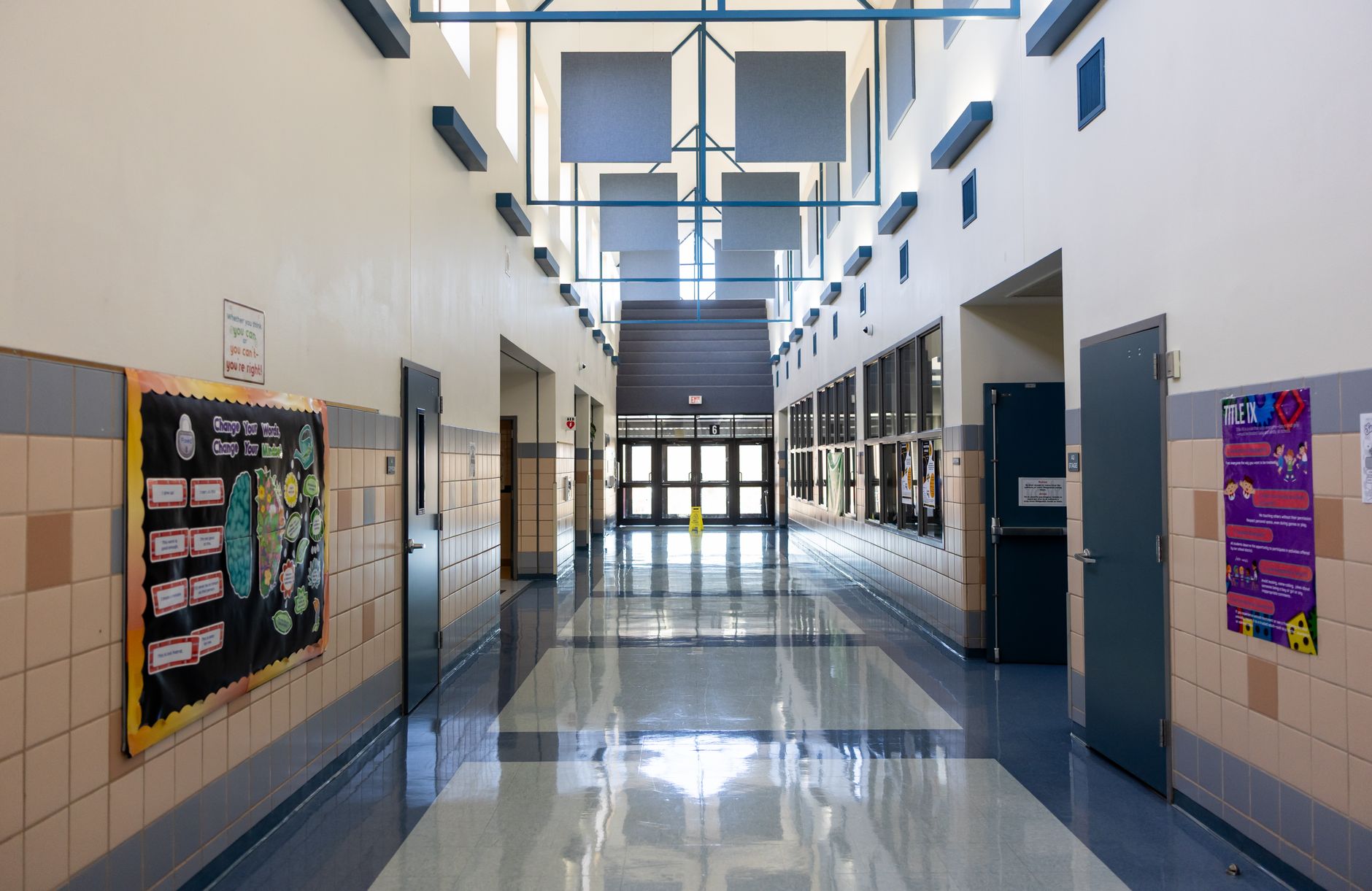 Clean and well-lit empty school hallway with bulletin boards and modern architecture.